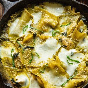 Top down shot of white chicken skillet lasagna in a pan topped with melted cheese and fresh basil