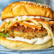 Side shot of crab cake sandwich on a plate with garlic aioli and coleslaw