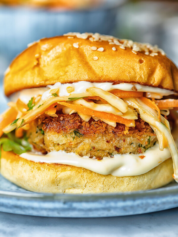 Side shot of crab cake sandwich on a plate with garlic aioli and coleslaw