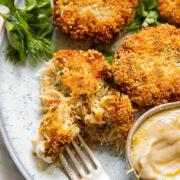 Close up shot of someone taking a bite of crab cake from a small plate
