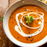 A bowl of spiced carrot and lentil soup on a wooden background