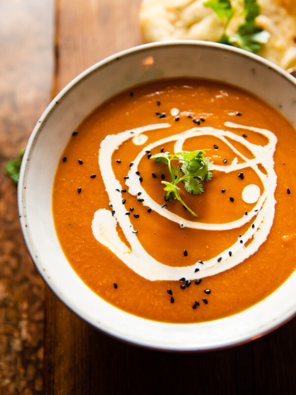 A bowl of spiced carrot and lentil soup on a wooden background
