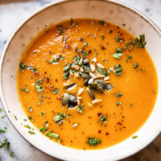 Bowl of sweet potato and carrot soup topped with seeds