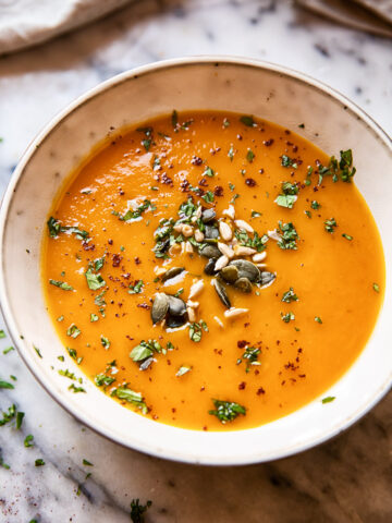 Bowl of sweet potato and carrot soup topped with seeds