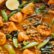 Sweet potato and lentil curry in a pan with serving spoon