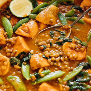 Sweet potato and lentil curry in a pan with serving spoon