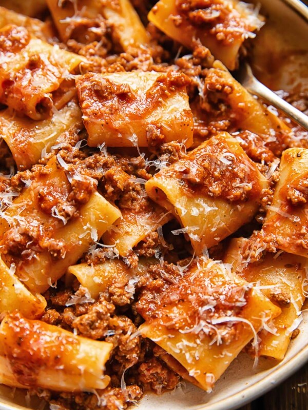 Close up shot of paccheri pasta in beef and tomato sauce with nduja and topped with Parmesan cheese