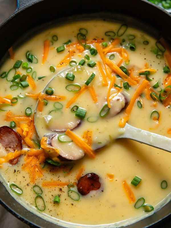 Top down shot of kielbasa soup in smooth potato blended broth being scooped out of a large pot