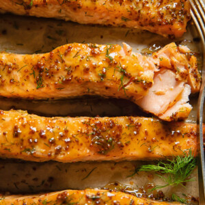 Close up shot of salmon fillets on a cooking tray topped with maple and mustard glaze
