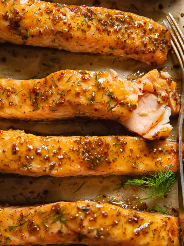 Close up shot of salmon fillets on a cooking tray topped with maple and mustard glaze