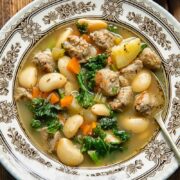 Top down shot of a spoon and a bowl of soup with sausage and white beans