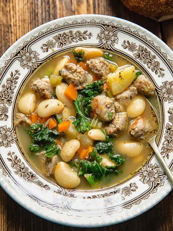 Top down shot of a spoon and a bowl of soup with sausage and white beans