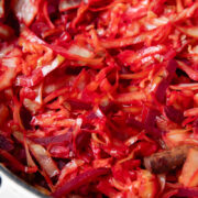 Close up shot of braised cabbage and beets in a large pot with bacon bits
