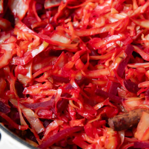 Close up shot of braised cabbage and beets in a large pot with bacon bits