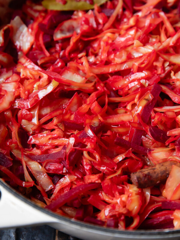 Close up shot of braised cabbage and beets in a large pot with bacon bits