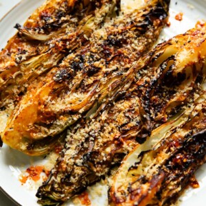 Close up shot of roasted cabbage on a plate, quartered and topped with breadcrumbs