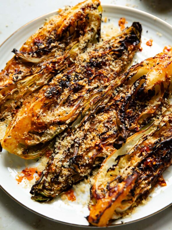 Close up shot of roasted cabbage on a plate, quartered and topped with breadcrumbs