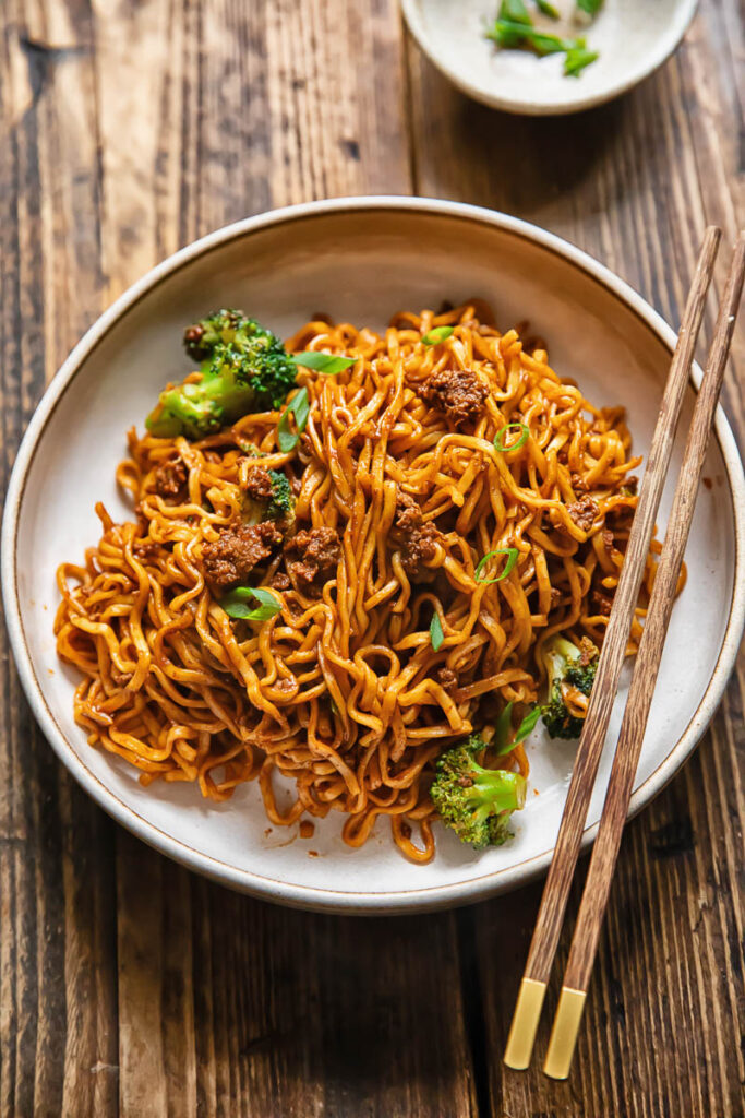 Top down shot of gochujang noodles with beef in a bowl with chopsticks