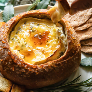 Top down shot of someone dipping bread in baked camembert
