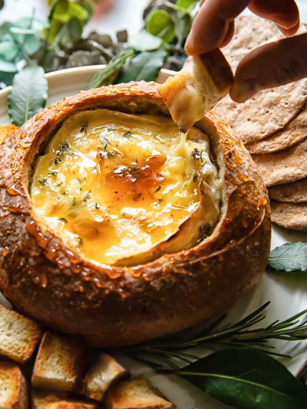 Top down shot of someone dipping bread in baked camembert