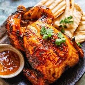 Top down shot of mango chutney roast chicken on a platter with naan bread topped with coriander