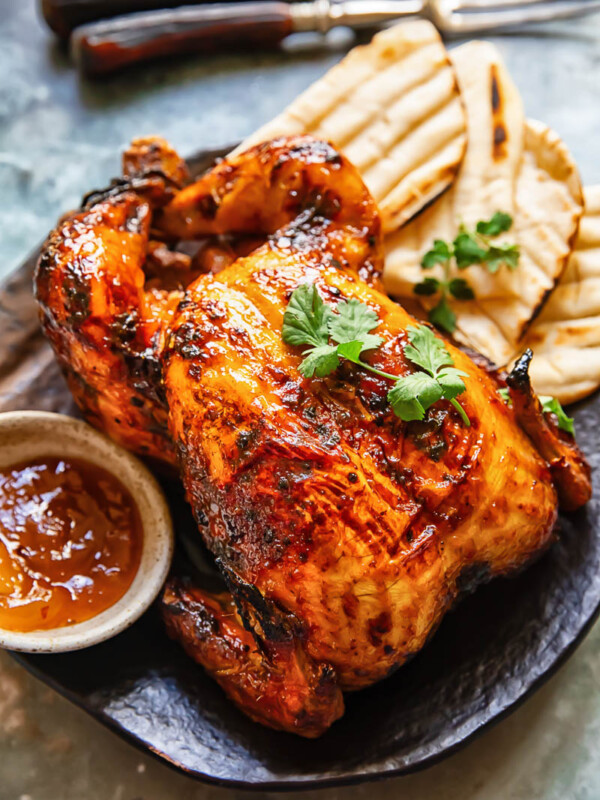 Top down shot of mango chutney roast chicken on a platter with naan bread topped with coriander