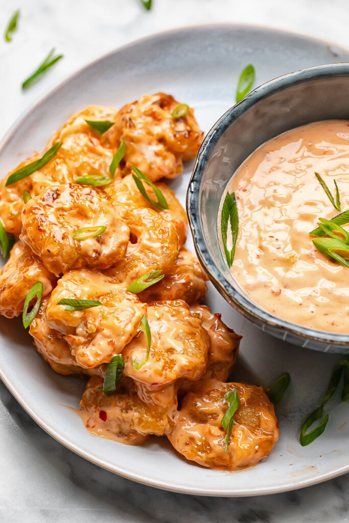 Top down shot of bang bang shrimp on a plate with a bowl of spicy mayo