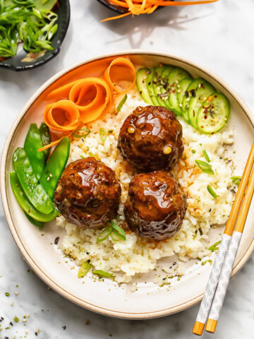 Close up shot of teriyaki meatballs with rice in a bowl with veg and chopsticks