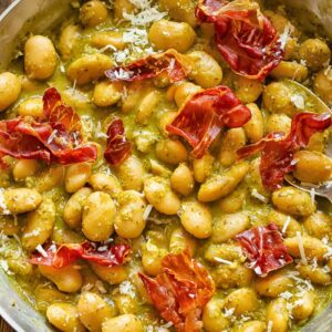 Top down shot of butter beans in a pan with creamy basil pesto sauce