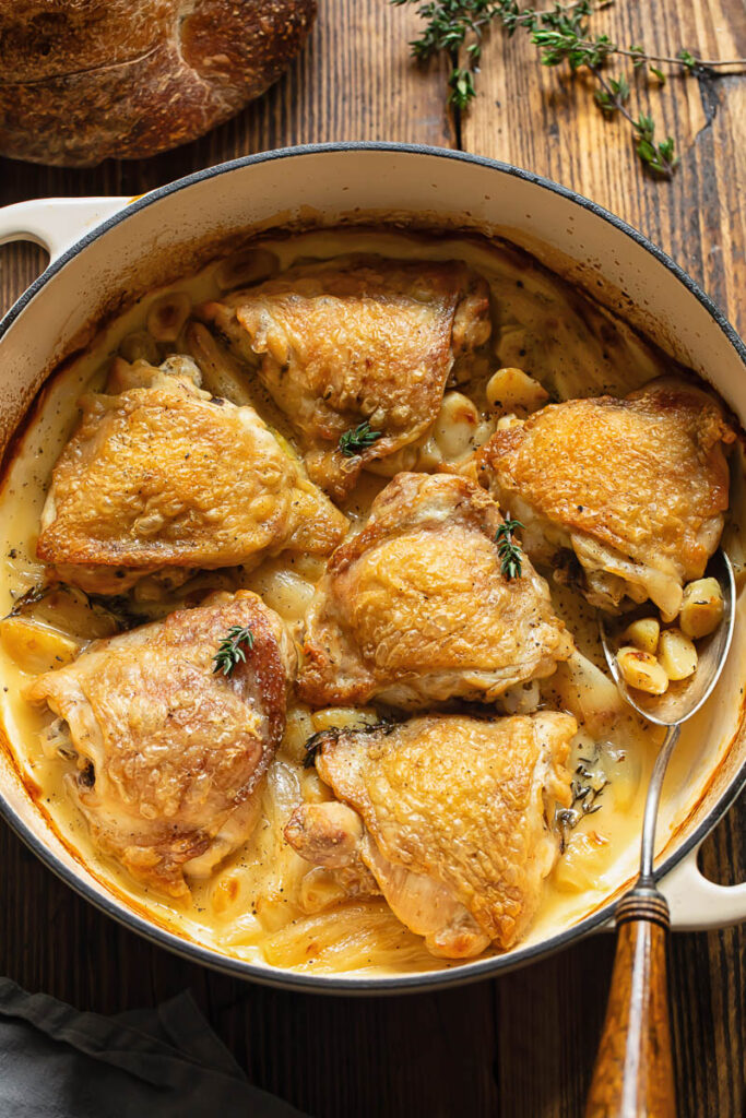 Top down shot of chicken with 40 cloves of garlic in a large wide pan