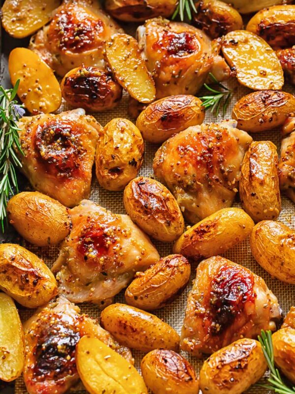 Top down shot of honey mustard chicken thighs in a baking tray with potatoes