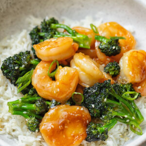 Close up shot of shrimp and broccoli stir fry on top of a bowl of rice