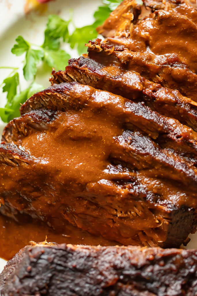Close up shot of beef brisket slices with gravy layered on top each other