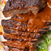 Top down shot of whole beef brisket on a large platter, topped with gravy