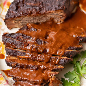 Top down shot of whole beef brisket on a large platter, topped with gravy