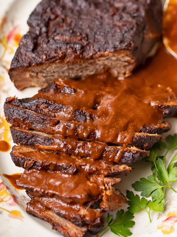 Top down shot of whole beef brisket on a large platter, topped with gravy