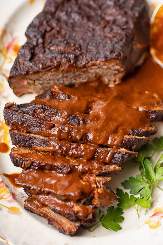 Top down shot of whole beef brisket on a large platter, topped with gravy