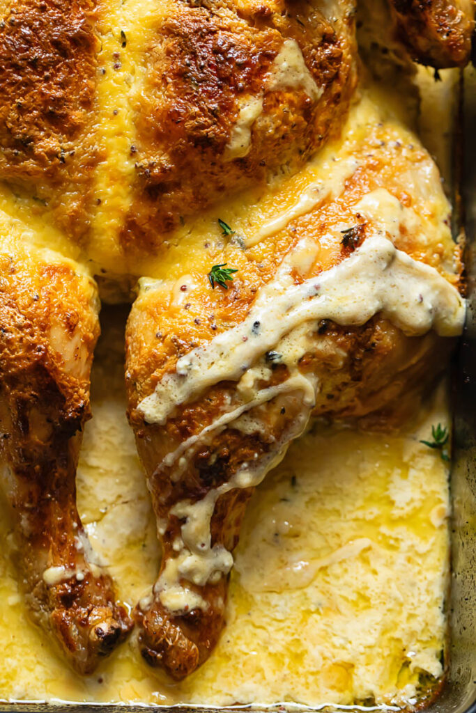 Close up shot of mustardy spatchcock chicken with garlic cream drizzle