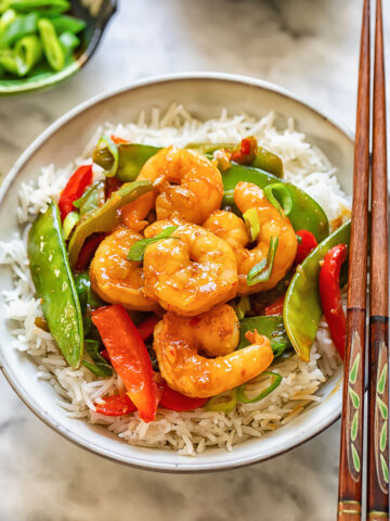 Top down shot of shrimp stir fry in a bowl with chopsticks