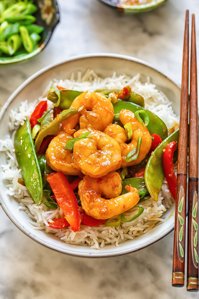 Top down shot of shrimp stir fry in a bowl with chopsticks