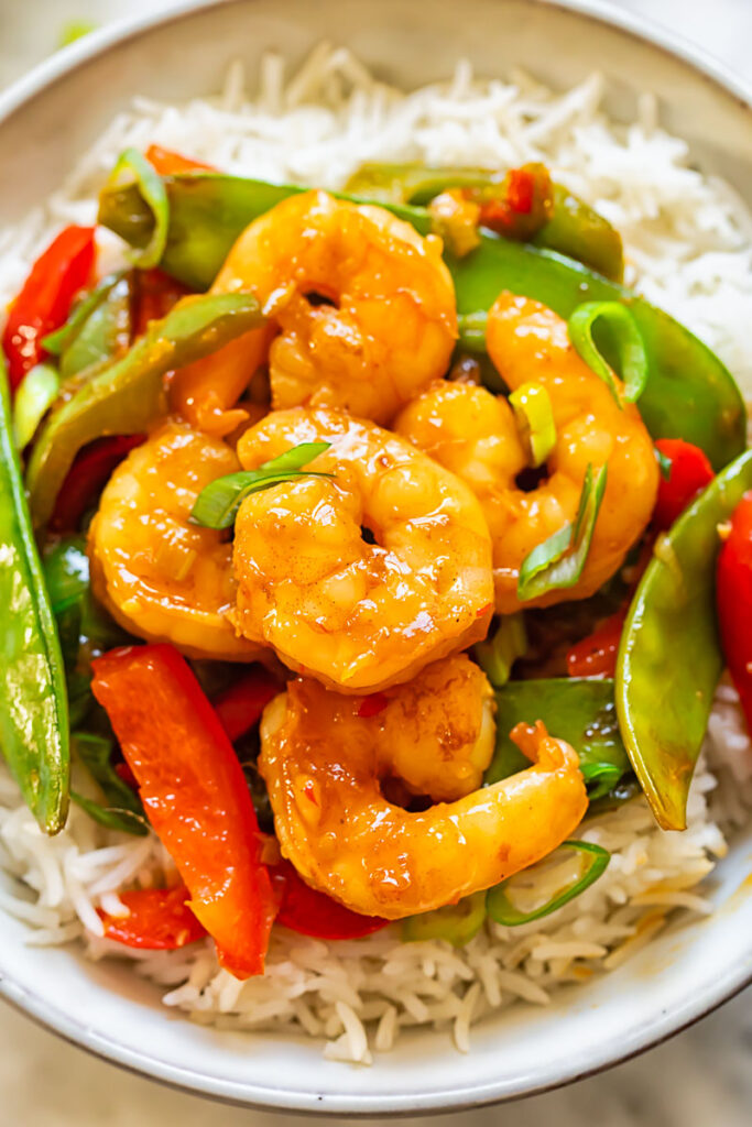 Close up shot of shrimp stir fry on top of rice in a bowl