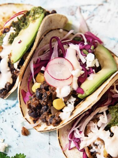 spread of three tacos with shredded vegetable son top