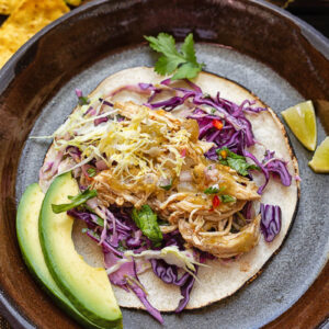 Top down shot of salsa verde chicken taco with slaw and avocado on a plate