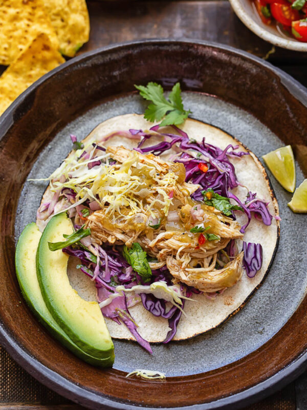 Top down shot of salsa verde chicken taco with slaw and avocado on a plate