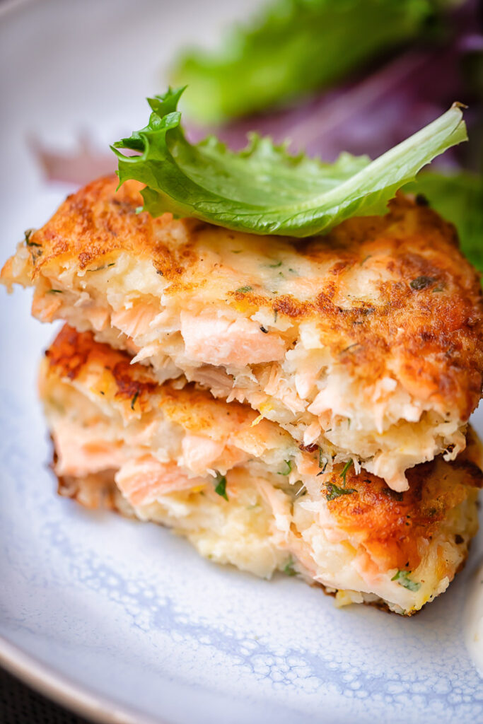 Close up shot of two pieces of salmon cake stacked on top of each other on a plate