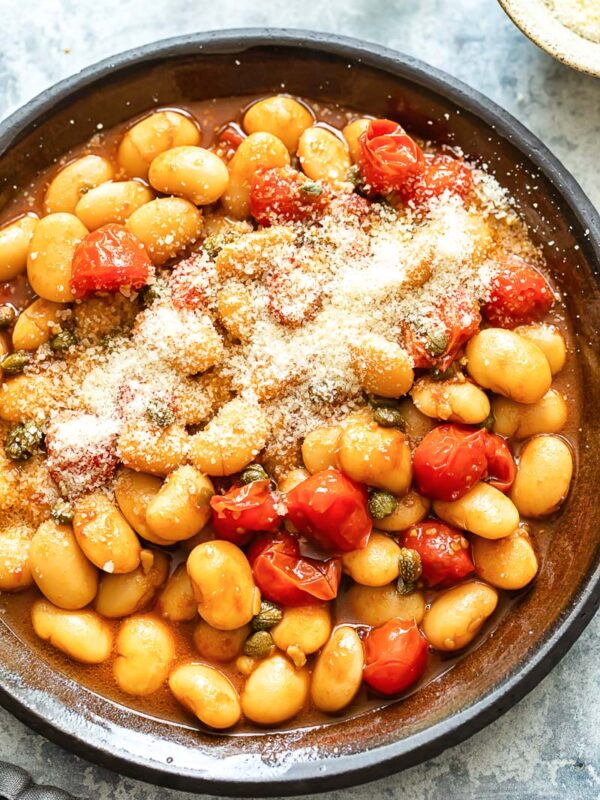 Top down shot of butter beans with cherry tomato sauce in a pan
