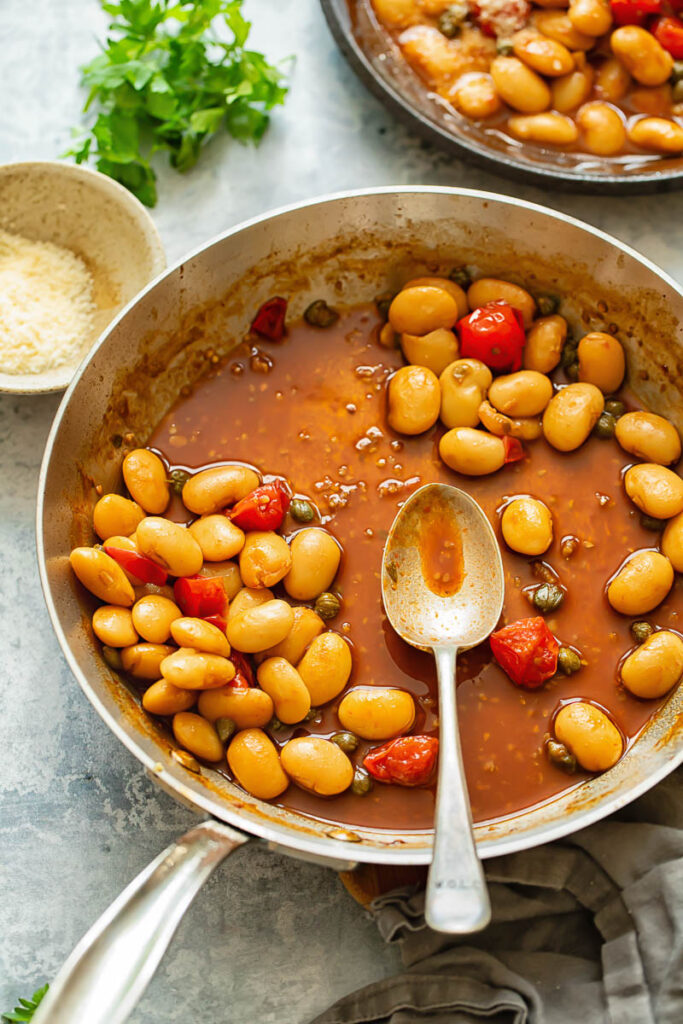 Top down shot of a spoon in a pan of beans with tomato sauce