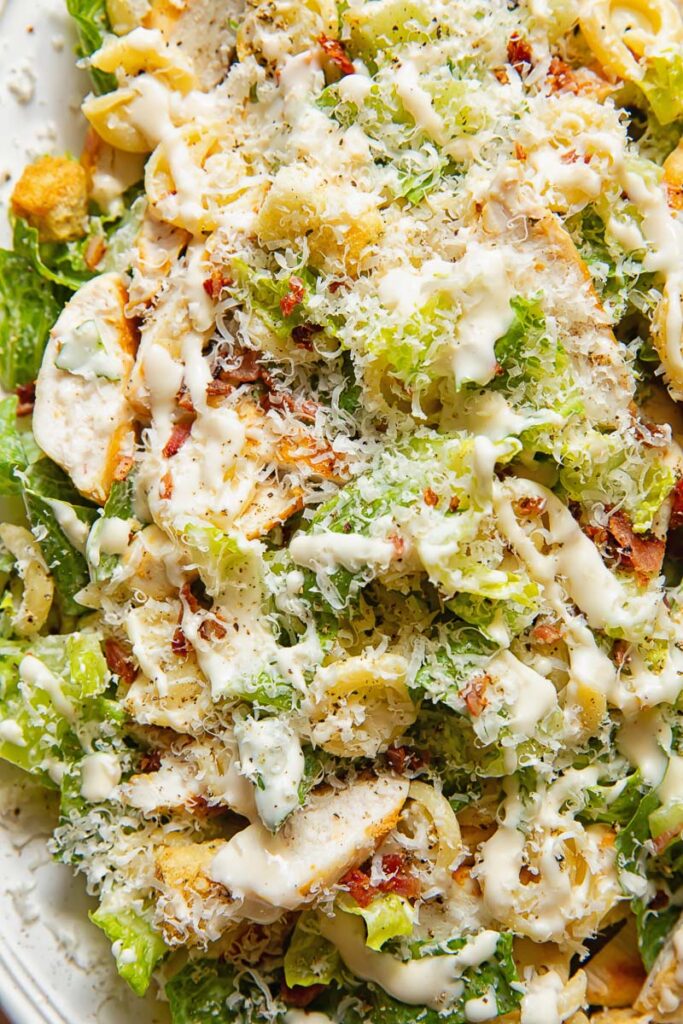 Close up shot of chicken Caesar pasta salad topped with grated Parmesan