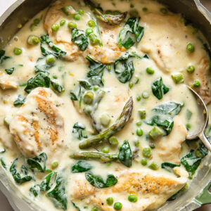 Top down shot of chicken primavera in a pan with creamy sauce