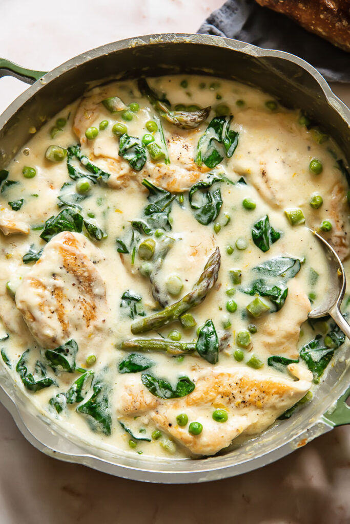 Top down shot of chicken primavera in a pan with creamy sauce